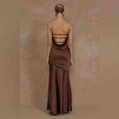 the back of a woman in a brown dress with cutouts on it's sides