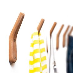 three pairs of scissors are hanging on the wall next to each other with wooden handles