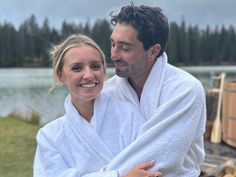 a man and woman wrapped in white towels by the water with their arms around each other