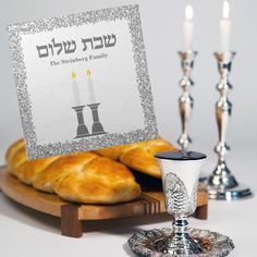 a table topped with bread and candles next to two silver candelabra holders