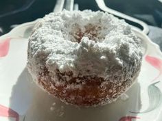 a powdered donut sitting on top of a white and red flowered plate