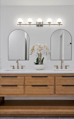 a bathroom with two sinks and three mirrors