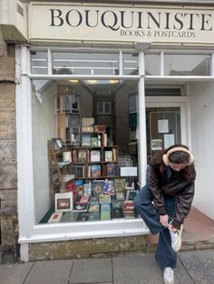 a person leaning against a store window with books in the front and behind it,