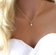 the back of a woman's neck wearing a necklace with a tear drop on it