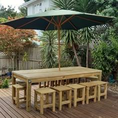 a wooden table and bench with an umbrella over it on a deck in the backyard