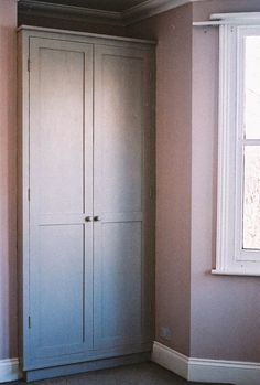 an empty room with a large white armoire next to a window in the corner