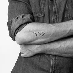 a man's arm with a small arrow tattoo on the left side of his arm