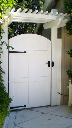 an open white door in front of a house with potted plants on the side