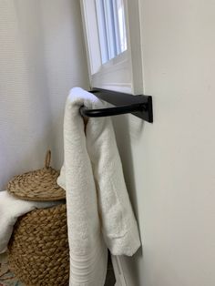 a towel is hanging on the wall next to a basket and door handle in a bathroom