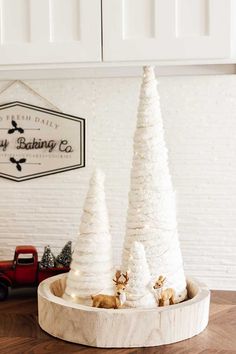 three white christmas trees sitting on top of a wooden tray