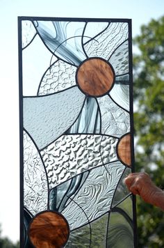 a hand holding up a stained glass window with trees in the backgroung