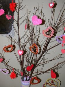 a vase filled with flowers and hearts on top of a table next to a wall