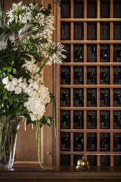 a vase filled with white flowers sitting on top of a wooden table next to a wine rack