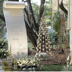 there is a sign that has been decorated with flowers and plants on it in front of some trees