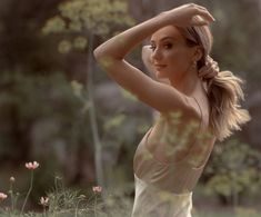 a woman in a white dress is posing for a photo with her hands behind her head