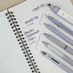 five pens and two notebooks sitting on top of each other next to each other