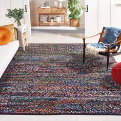 a living room with white walls and colorful rugs on the floor next to a chair