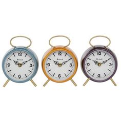 three different colored clocks sitting next to each other on top of wooden sticks with metal handles