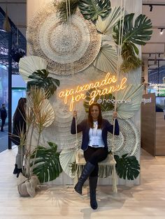 a woman is sitting on a bench in front of a wall with plants and lights