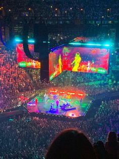 a large crowd is watching a concert in an arena with bright lights on the stage