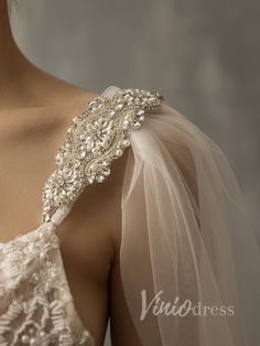 the back of a woman's wedding dress with beading on it and veil over her shoulder