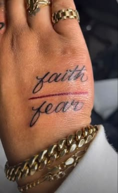 a woman's hand with the words faith and fear tattooed on it