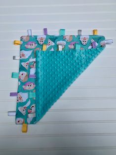 two baby bibs hanging on the wall with pegs attached to them and one has an animal design