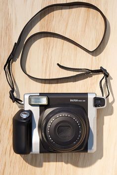 an old fashioned camera sitting on top of a wooden table next to a black and white strap