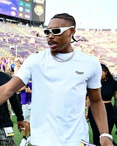 a man with sunglasses on his head standing in front of a crowd at a football game