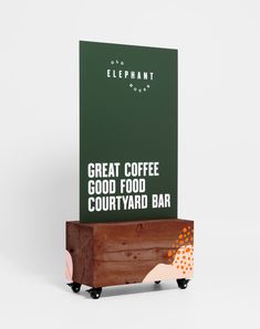 a wooden box sitting on wheels next to a sign that says great coffee good food courtyard bar