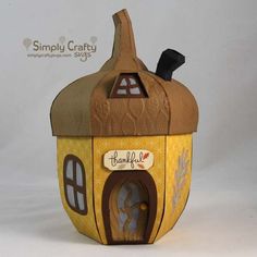 a small yellow and brown house with a black cat on top