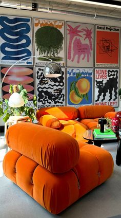 an orange couch sitting in front of a wall with pictures on it