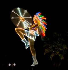 a woman is dancing in front of a clock with lights on her body and head