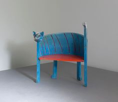 a blue and red bench sitting on top of a gray floor next to a white wall