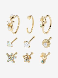 six pairs of gold tone nose rings with crystal stones and seashells on them