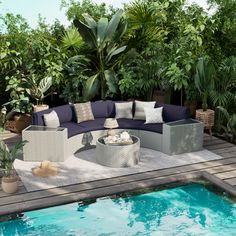 an outdoor living area next to a pool with lots of plants and furniture around it