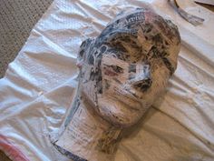 a paper mache head sitting on top of a white sheet