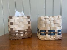 two baskets sitting on top of a wooden table next to each other, one with a tissue dispenser in it