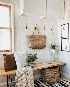 a bench with two baskets hanging on the wall next to it and a rug in front of it