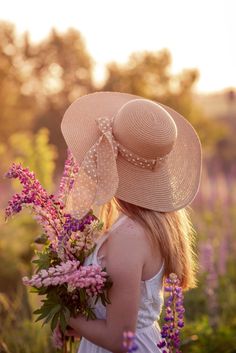 a woman wearing a hat and holding flowers