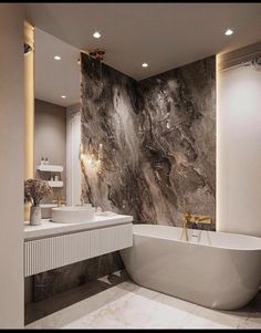 a bathroom with marble walls and flooring, two sinks and a large bathtub