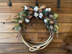 a wreath hanging on the side of a wooden wall with cotton balls and greenery