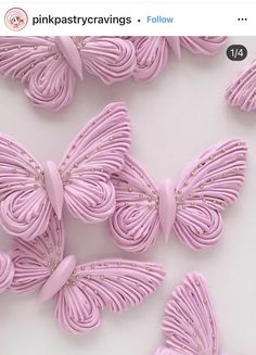 some pink butterflies are on a white surface and one is made out of fondant