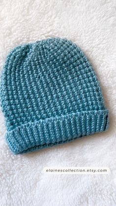 a blue knitted hat sitting on top of a white blanket