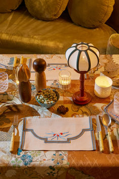 the table is set with dishes, candles and other things to eat on it's placemats