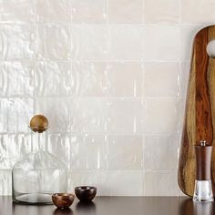 a wooden cutting board sitting on top of a counter next to other kitchen utensils