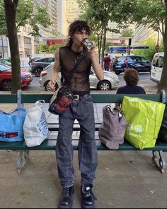 a man drinking from a cup while sitting on a bench