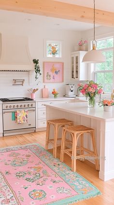 a white kitchen with pink rugs and flowers on the counter top in front of an oven