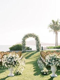 an outdoor ceremony setup with white flowers and greenery on the lawn, overlooking the ocean