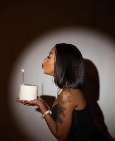 a woman holding a cake with a candle in it and looking up at the sky